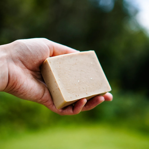 Une main qui tient un savon naturel fait au Québec, à l'avoine, au miel et au romarin